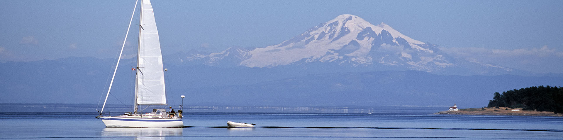 A Sailboat with blue sky and mountain in the distance.