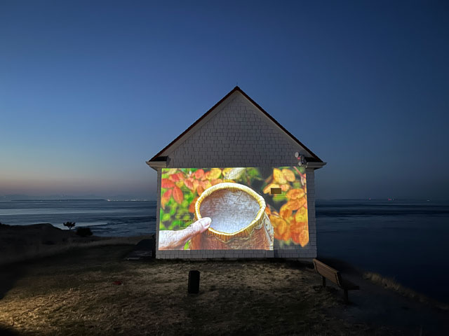 A movie projecting on a small white building