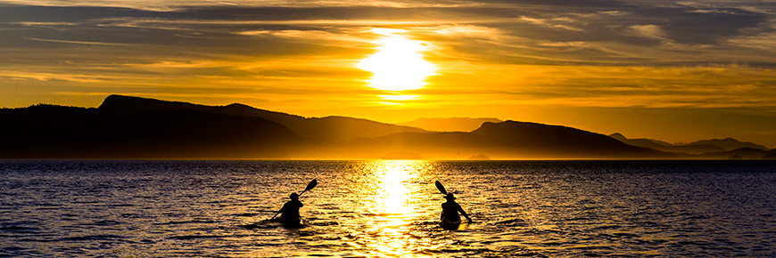 Depuis l'Île Pender, deux kayakistes pagaient vers le coucher du soleil près de l'Île Pender