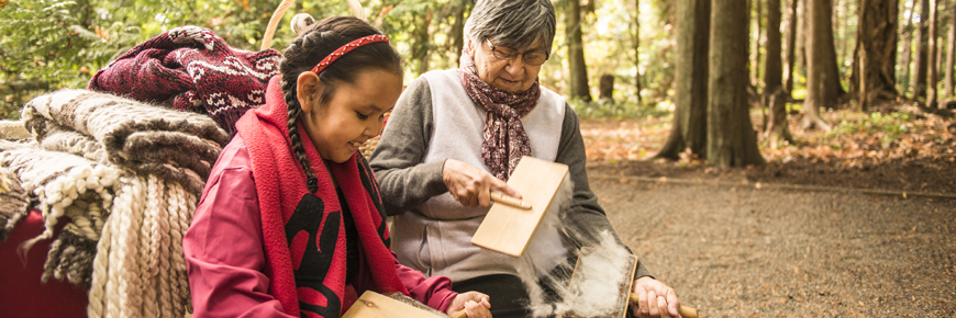 A First Nations elder cards wool with her granddaughter.