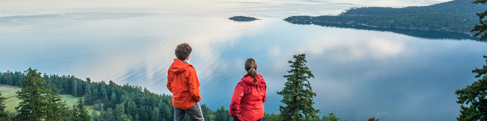 Two people standing on a hill looking at a body of water