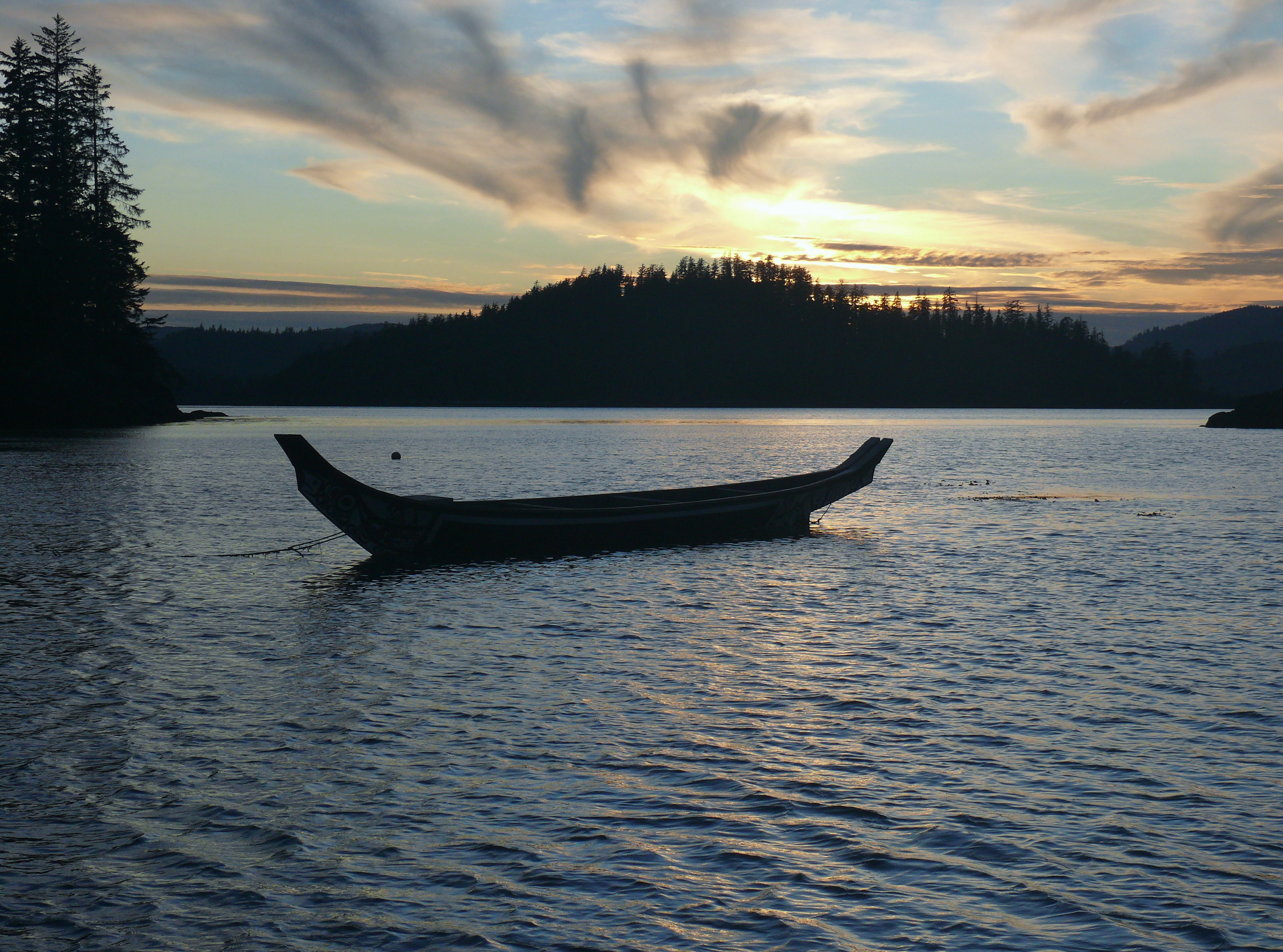 Un canot flotte sur les eaux calmes au coucher du soleil