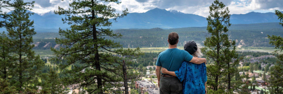 A couple stand together facing the view of the valley