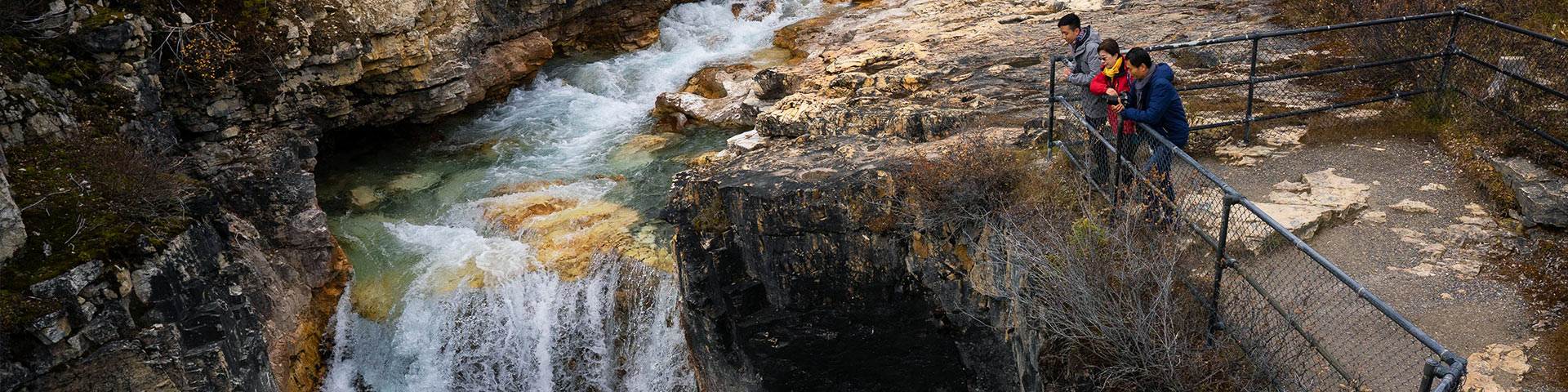 A group of people look at a waterfall in Marble Canyon