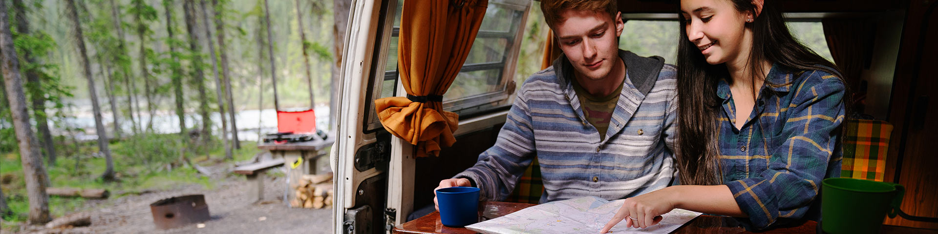 A couple inside a campervan look at a map