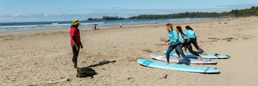 Young people learning to surf on the beach with a surf instructor.