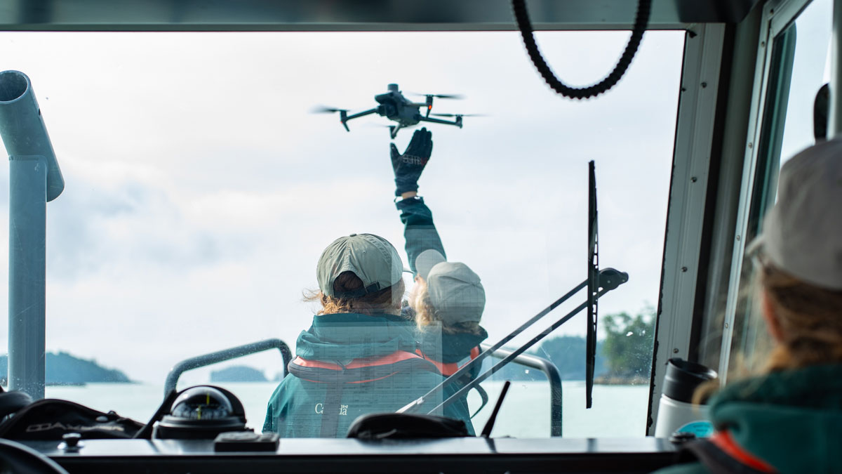 a person at the front of a boat with a drone in hand