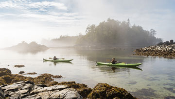 Two people paddling their kayaks in the Broken Group Islands