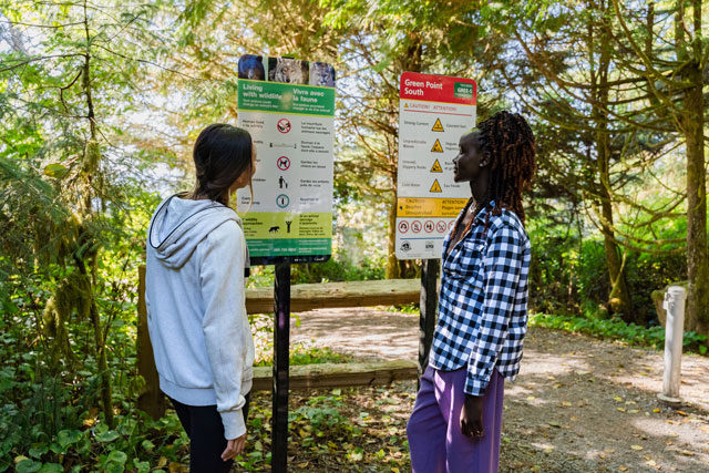 two people looking at Wildlife Safety signage in the forest