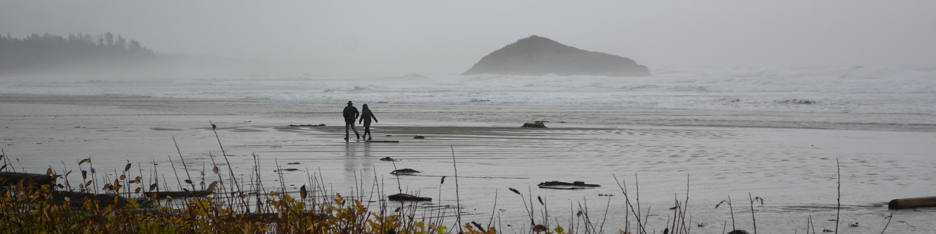 deux personnes marchant sur une plage balayée par la tempête