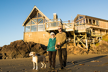 A couple with a dog on leash in front of the Kwisitis Visitor Centre