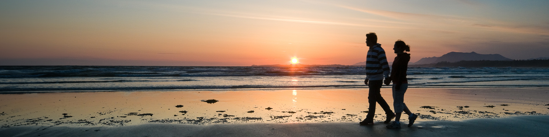 Un jeune couple marche sur la plage lors d'un coucher de soleil.