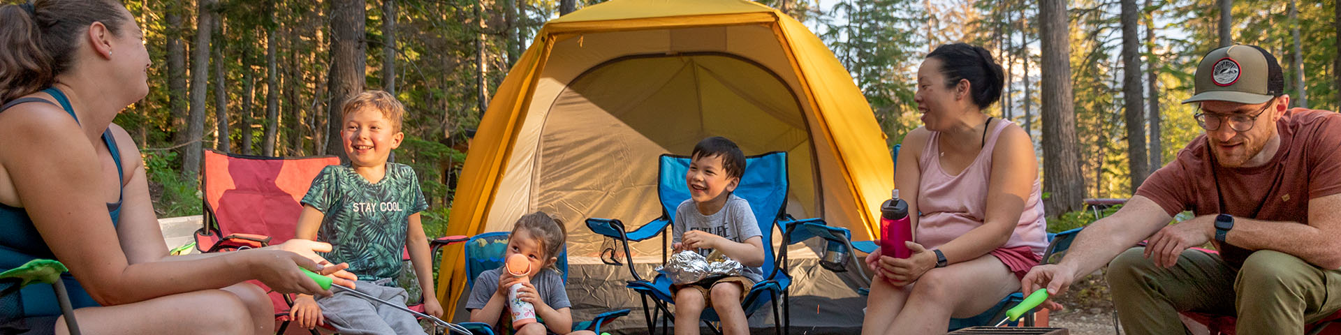 Groupe de 6 avec adultes et enfants assis dans un camping