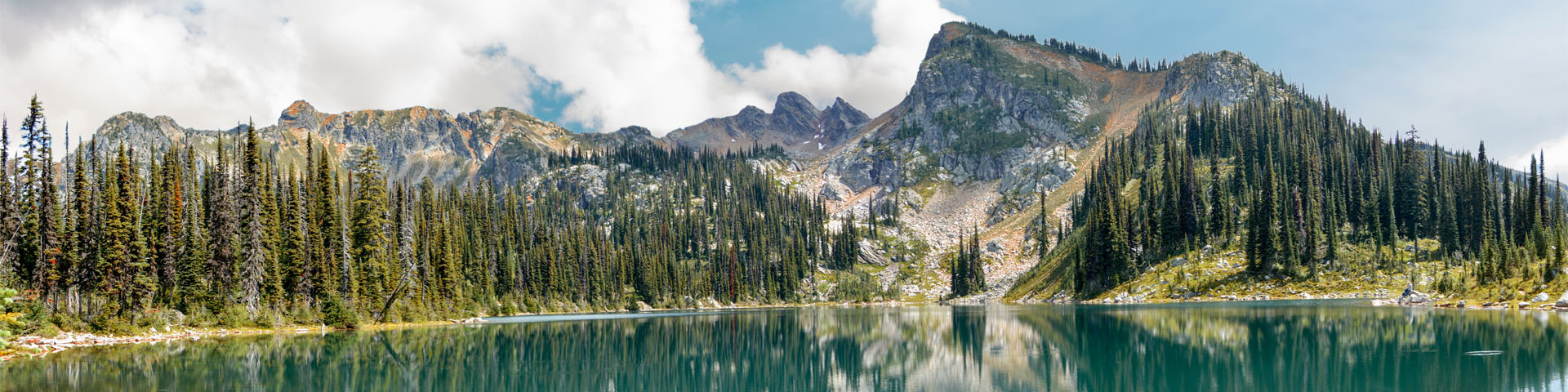 Landscape photo of an alpine setting with a mirror-like lake in the foreground