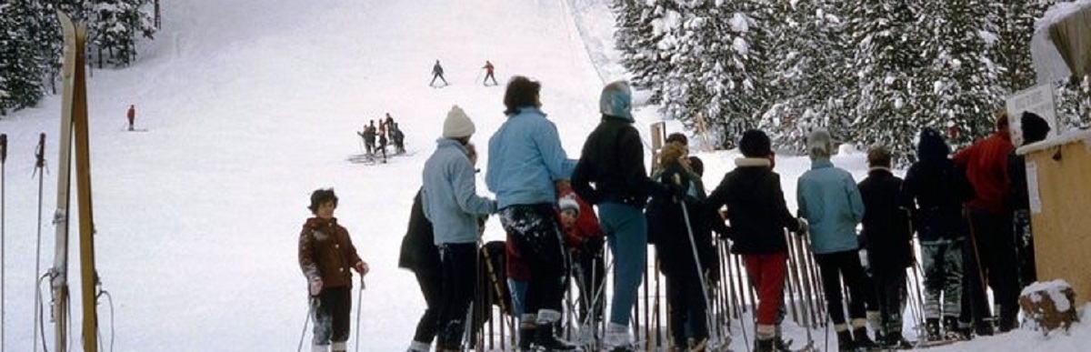View of the slope of the old ski hill on the Tally-Ho trail, with skiers and people queuing at the ski lift.