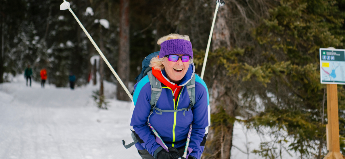 A cross-country skier launches into a slope with a smile.
