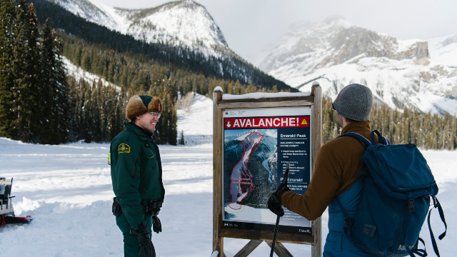 Un garde de parc discute avec un excursionniste de l’arrière-pays d’un panneau sur les risques d’avalanche au lac Emerald au parc national Yoho .