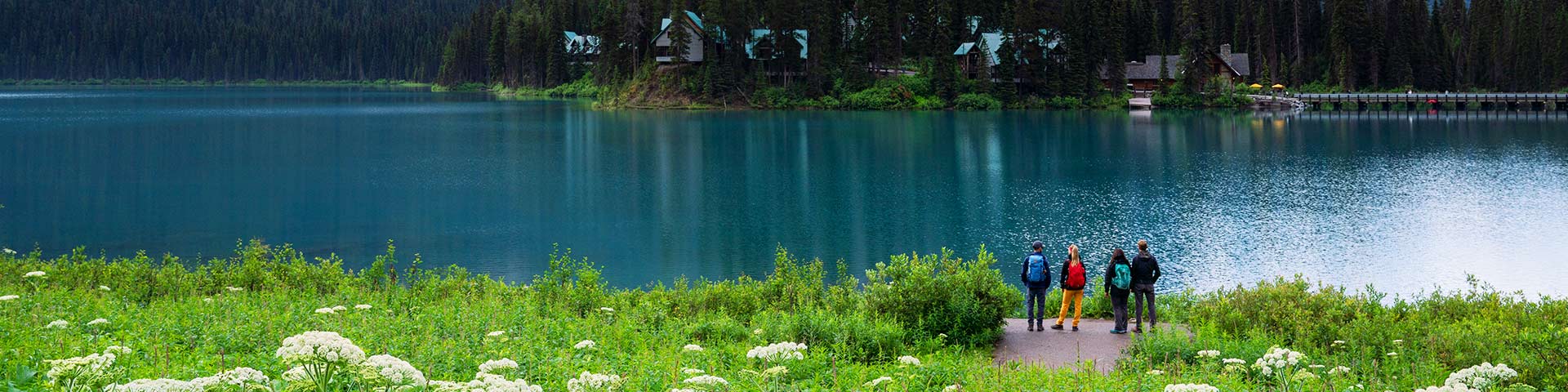 Four people stand on the Emerald Lake lakeshore enjoying the view