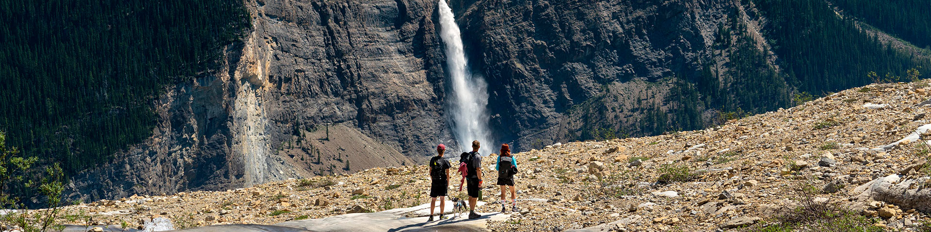 Hikers stand enjoying the view of a waterfall across the valley