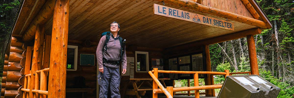 Un homme se tient debout sous le porche couvert de l’abri de jour Le Relais.