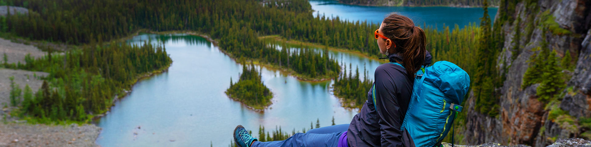 A hiker sits overlooking lakes below