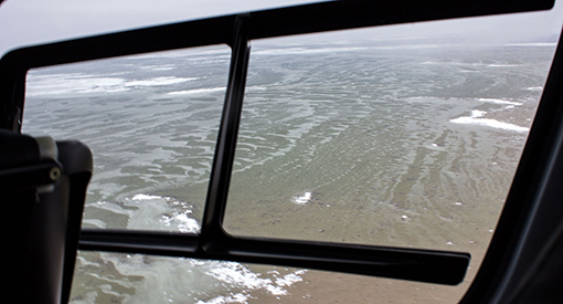 Large ponds are seen through the window of a helicopter.