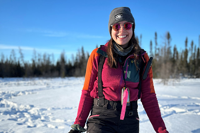 Une chercheuse marche dans la neige, munie d’un sac fourre-tout dans le parc national Wapusk.