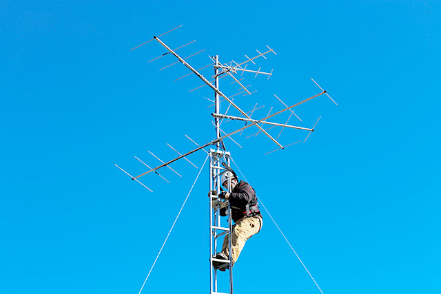 Une personne se tient sur une échelle près du sommet d’une tour de signalisation.