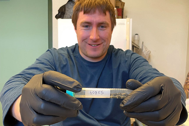 Une personne portant des gants tient un tube d’excréments de caribou dans un laboratoire.
