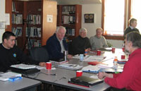 Cinq personnes sont assises à une longue table rectangulaire. 