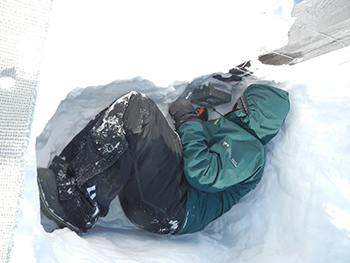 Un employé de Parcs Canada creuse la neige pour trouver un appareil photo.