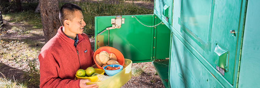 Un campeur range de la nourriture dans le casier à provisions d’un camping. 