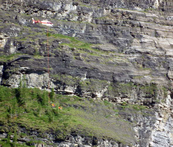 2. A Visitor Safety Specialist slinging the first subject from the ledge as the second specialist rigs the second subject. 