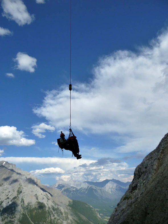 A Visitor Safety Specialist slings the patient to Banff EMS at a staging area. 