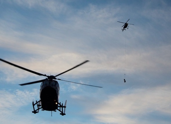 A Visitor Safety Specialist is slung to the staging area as the STARS helicopter takes off with the patient.