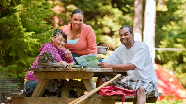 Three people at a picnic table reading a map.