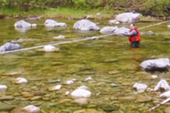 Hiker crossing water holding rope