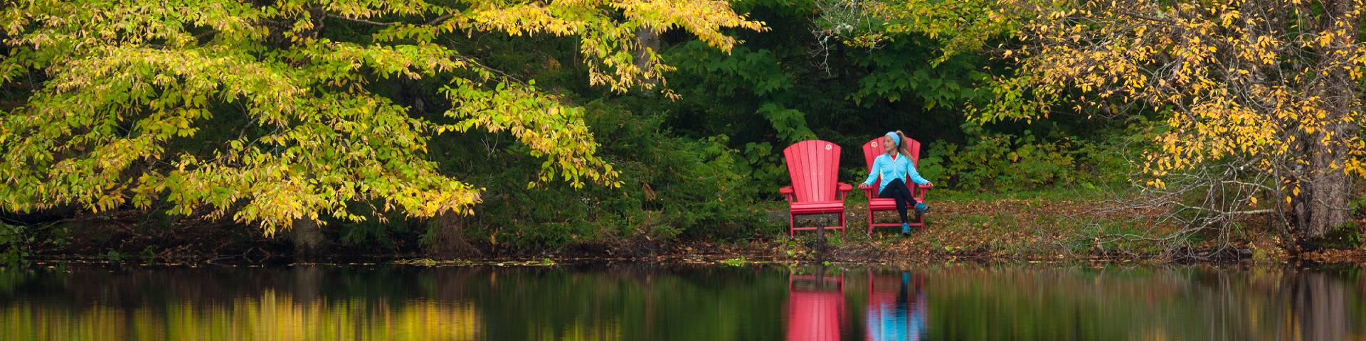 A person sitting in a red chair next to a lake