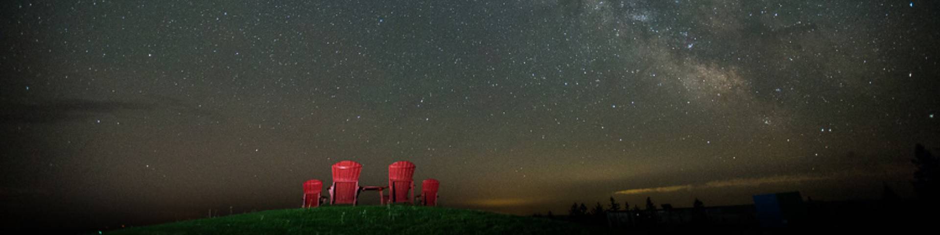 Four red chairs under a dark, starry sky