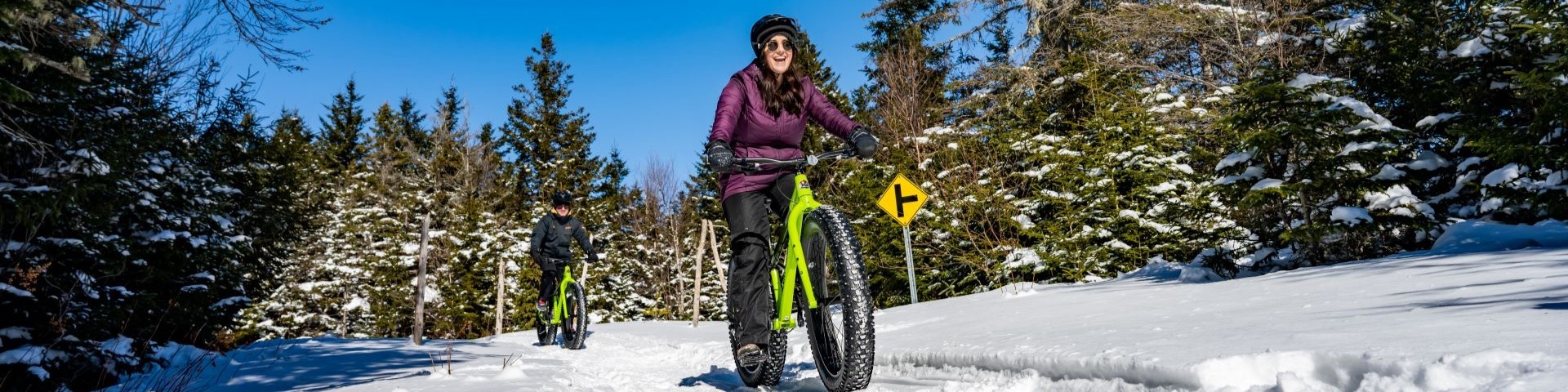 Two cyclists riding on a groomed trail in winter. 