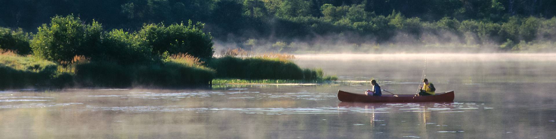 Two friends on a canoe fishing on the lake