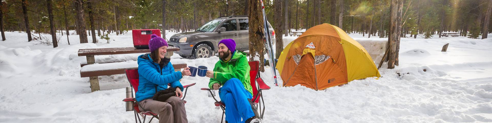 A couple near a tent in the snow