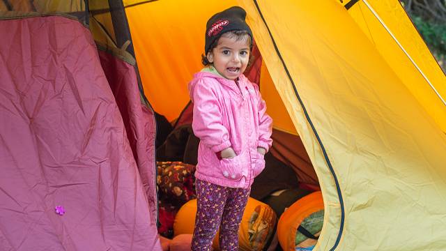 A young child standing in a yellow tent