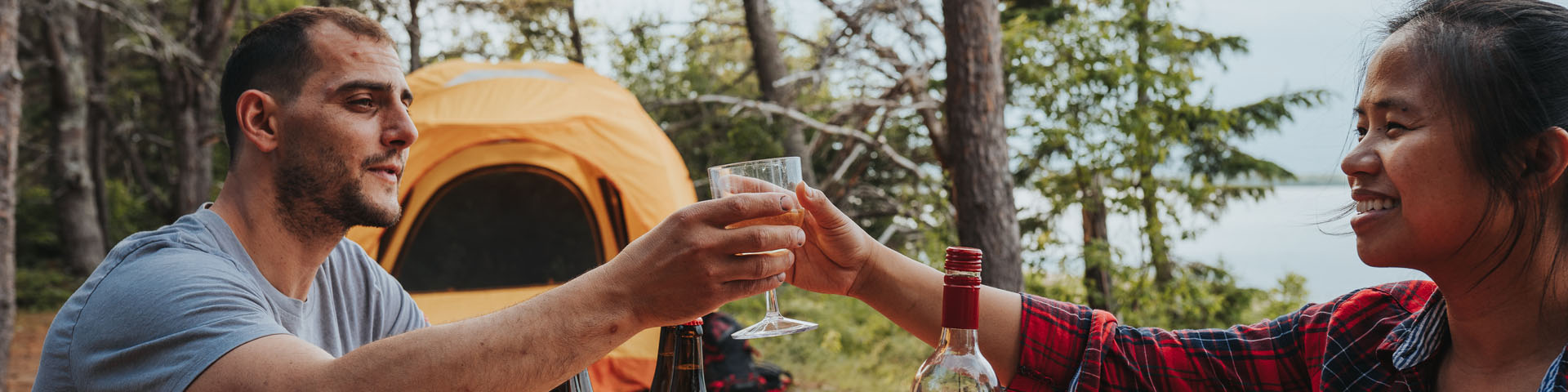 Un couple célèbrent avec un verre près de leur tente.
