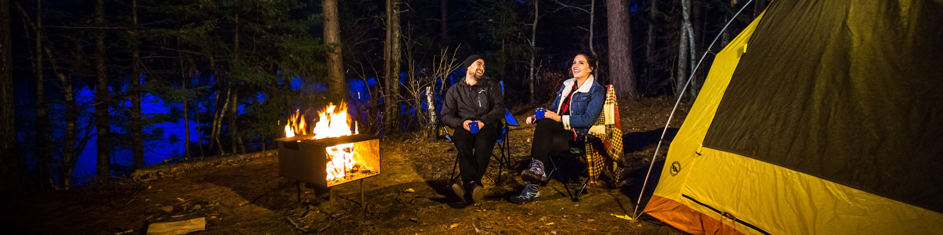 A couple sitting by the fire at their backcountry camping site.