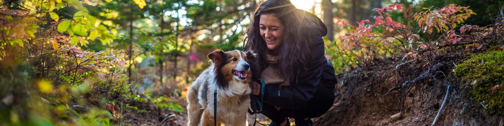 Une visiteuse avec son chien dans un sentier.