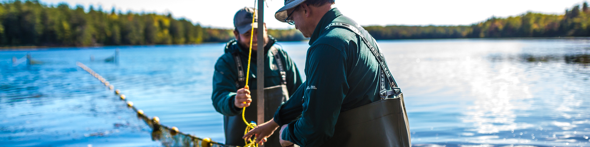 Des agents de la conservation des ressources en bateau, tenant un filet de pêche.