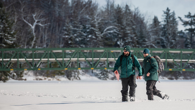 Des employés de Parcs Canada en conservation des ressources sur une rivière gelée.