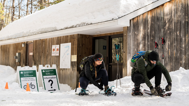 Deux visiteurs attachent leur raquettes en face de l'abri de fartage de Pijeboogwek.