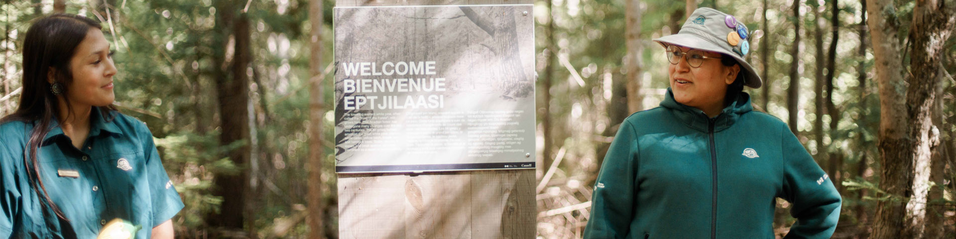 Two Parks Canada interpreters on a trail in the woodland.